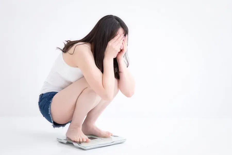 体重計の数字に落ち込む女性